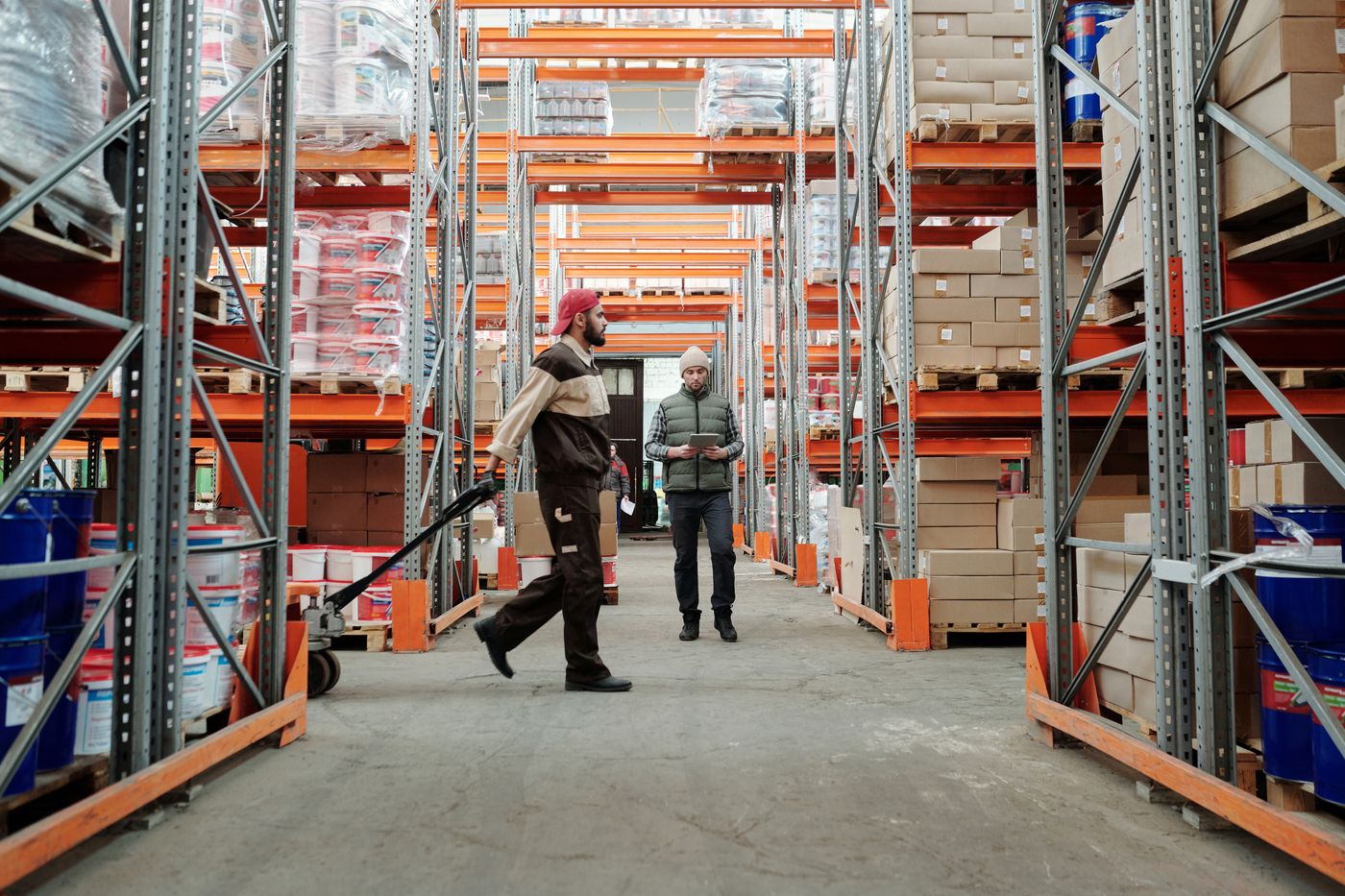 Two workers managing stock in a warehouse aisle
