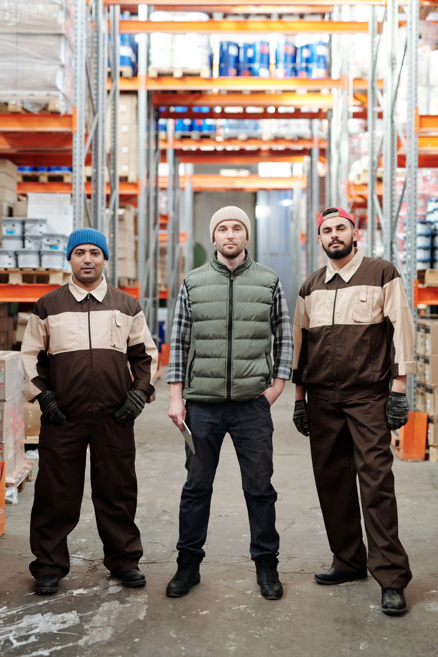 Three warehouse workers in uniform in an organised storage area